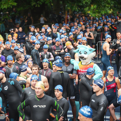 maskottchen Trinity steht mitten in der Startgruppe für das Schwimmen